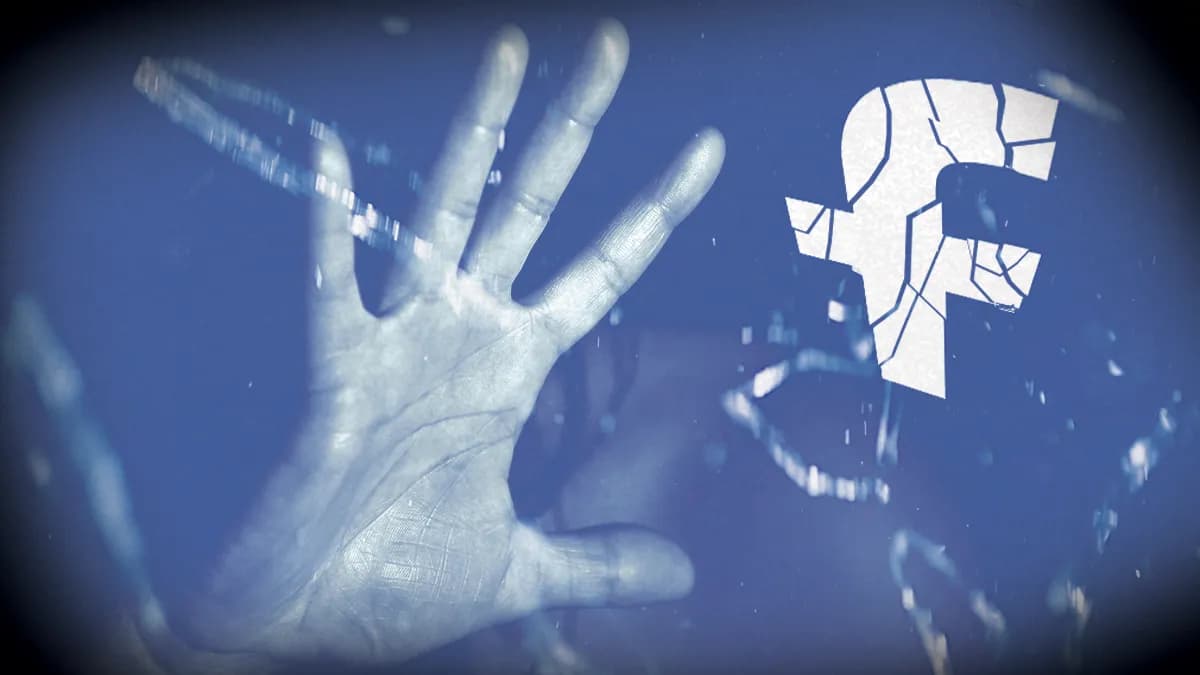 a hand against a cracked facebook logo