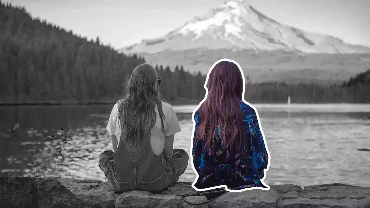 world in grey color, while two girls sitting and looking at nature, one of the girl is in color